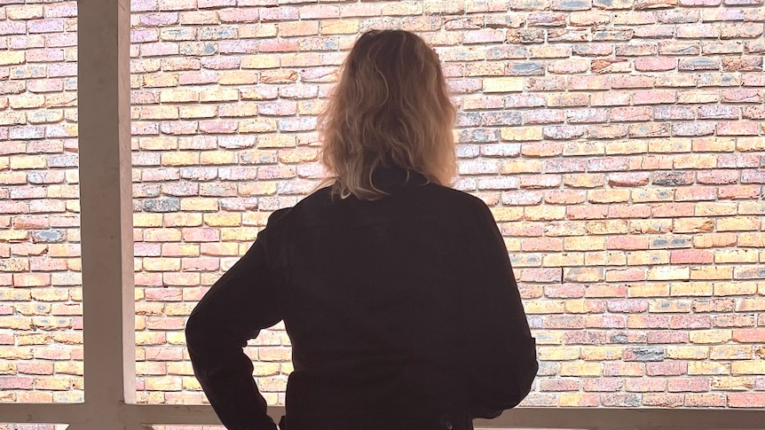 The back profile of Brisbane sex worker Millie, standing on a verandah 