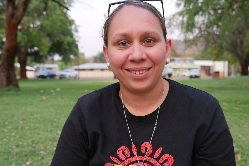 An Indigenous woman with a yes t-shirt smiles to the camera