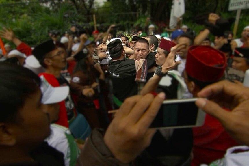 A group of Habib Rizieq supporters grab a man suspected of being a police informer during a protest in Jakarta.