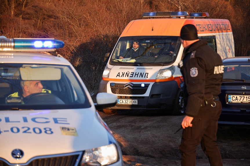 An ambulance leaves the site after at least 18 people were found dead in Bulgaria in an abandoned truck.