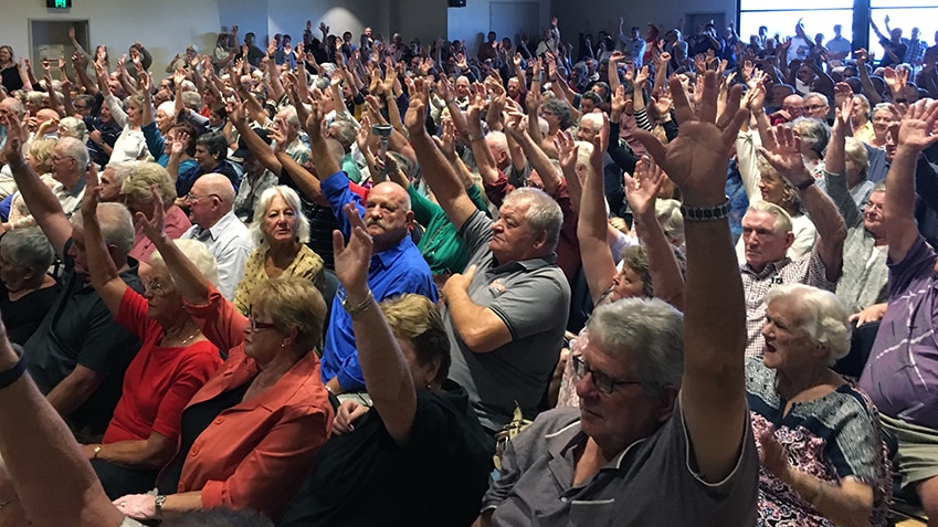 A crowd of 500 seated people with their hands raised