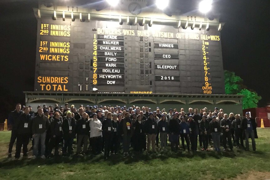 A group of people standing under a historic scoreboard