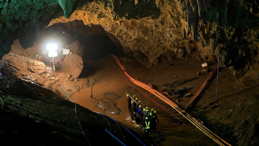 A wide photo inside the cave shows rescue workers, equipment and lights set up