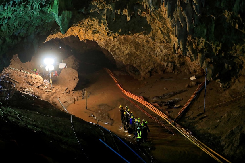 A wide photo inside the cave shows rescue workers, equipment and lights set up