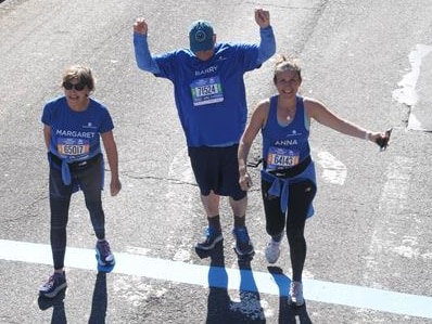 An aerial shot of three runners celebrating on a road.