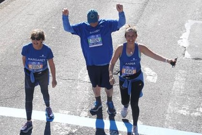 An aerial shot of three runners celebrating on a road.