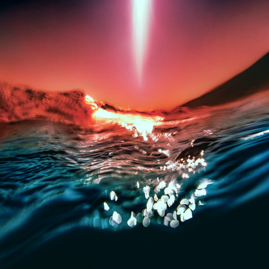 close up of ocean water and a sunset in the background