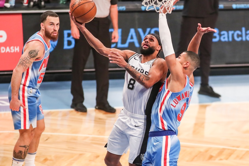 Basketball player goes for a lay-up with a defender trying to block to the left of him.