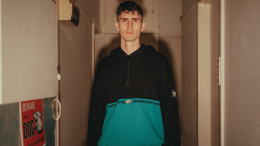 Press shot of Running Touch; standing in hallway, wearing two-tone black and teal jumper