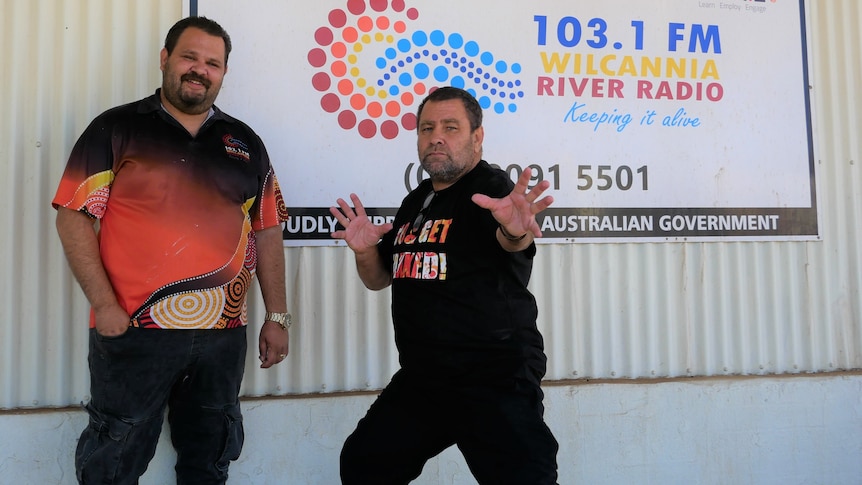 Two men post for a photo in front of the Wilcannia River Radio station.