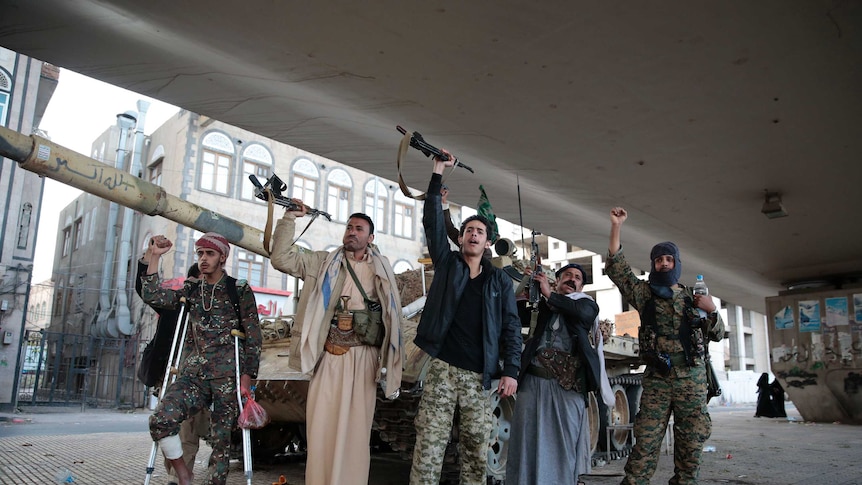 Militants standing with their arms and guns raised.