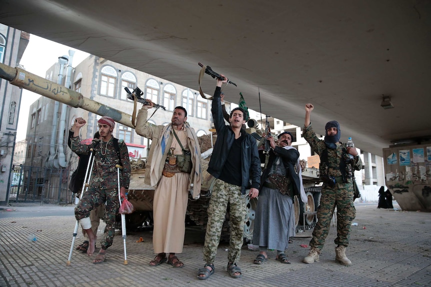 Militants standing with their arms and guns raised.