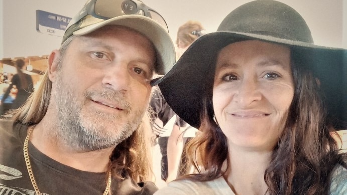 Two people, wearing hats, smile in a selfie