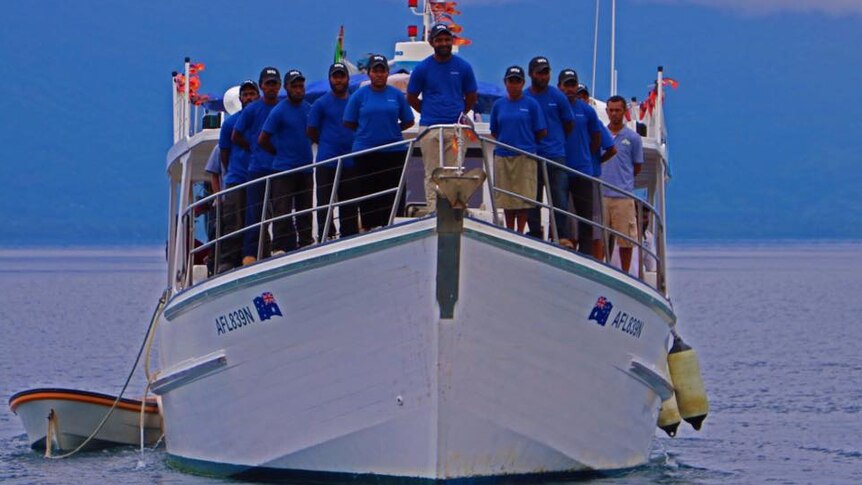 A boat with people standing on the deck posing for a photo.