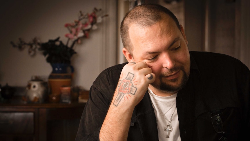 Christian Read sits at a table and rests his head on his hand.