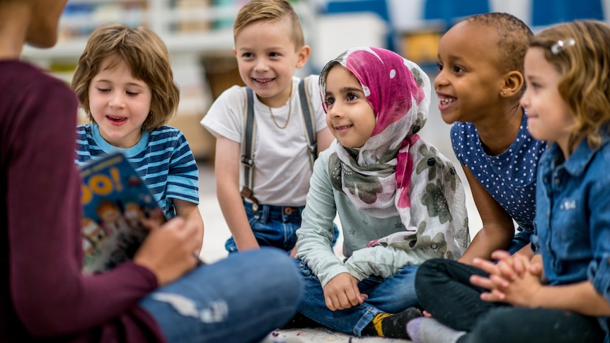 Children listening to teacher read at preschool