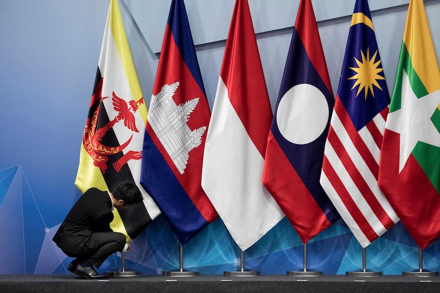 Seorang pekerja menyesuaikan bendera Brunei dengan bendera Kamboja, Indonesia, Laos, Malaysia dan Myanmar
