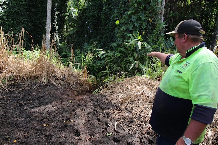 Farmer is high visibility shirt pointing out soil damage on his farm 