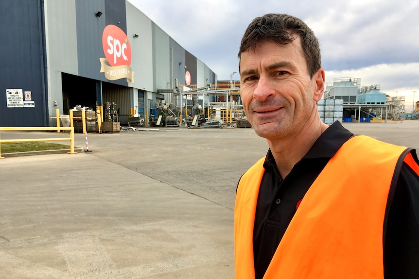 SPC Manager David Frizzell in high vis vest standing outside SPC factory in Shepparton Victoria, with SPC sign in background.