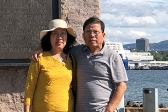 A man and a woman in a holiday snap in front of a statue.