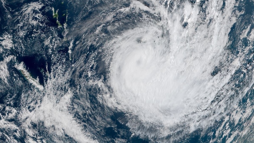 A satellite image of the South Pacific shows a portion of the Earth covered by a large cyclonic storm.