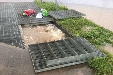 Churning floodwaters can be seen just below the surface of an open grate