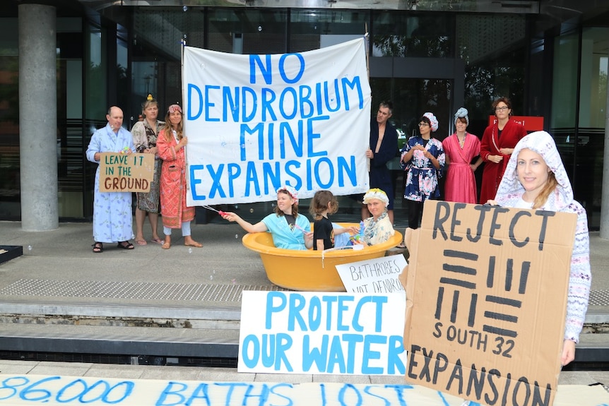 Protestors hold signs saying 'No Dendrobium mine expansion.'
