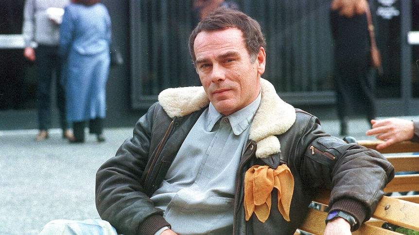 Dean Stockwell sits on a bench.