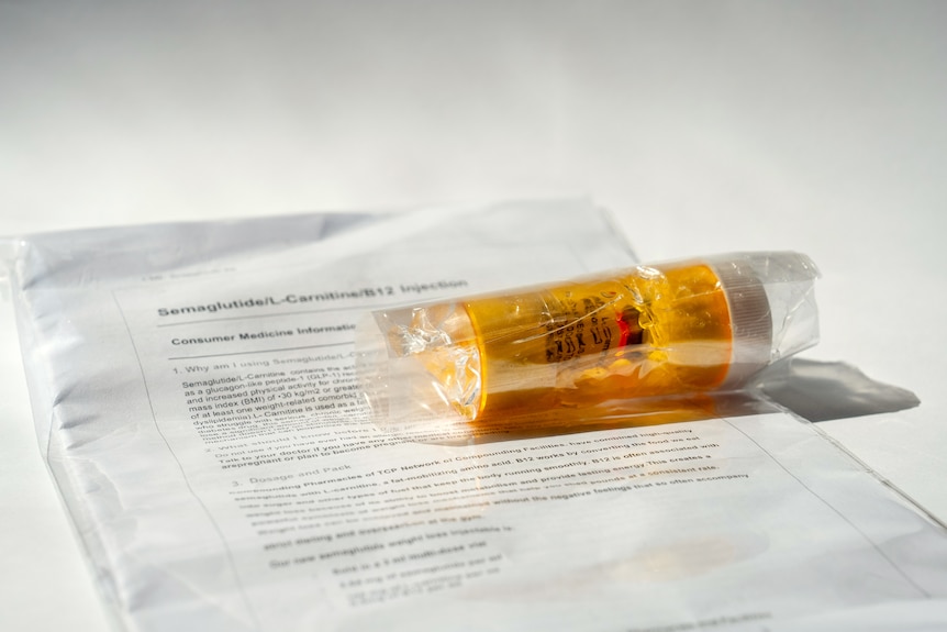 A small yellow container containing a vial of red liquid, sits on a sheet of paper with information about Semaglutide.