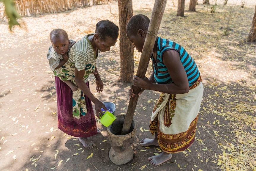 Theresa Elias, 53, and her Granddaughter, also named Theresa, pound masawu fruit to make it edible