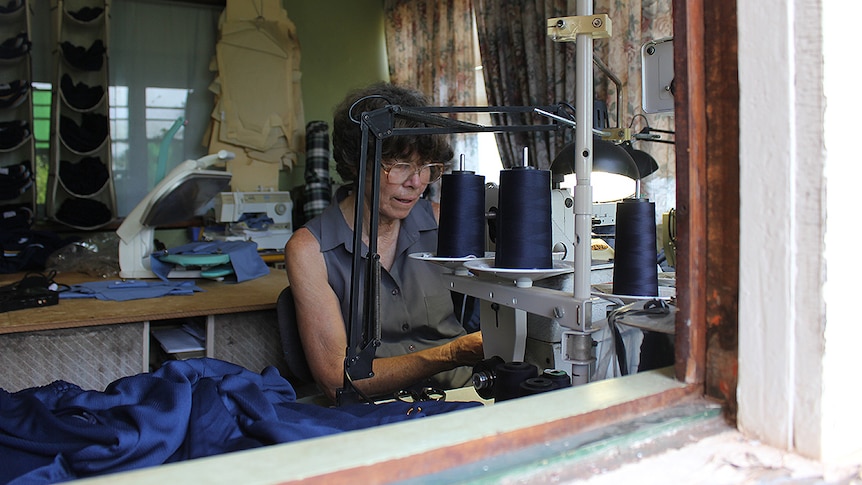 A woman sits at a sewing machine