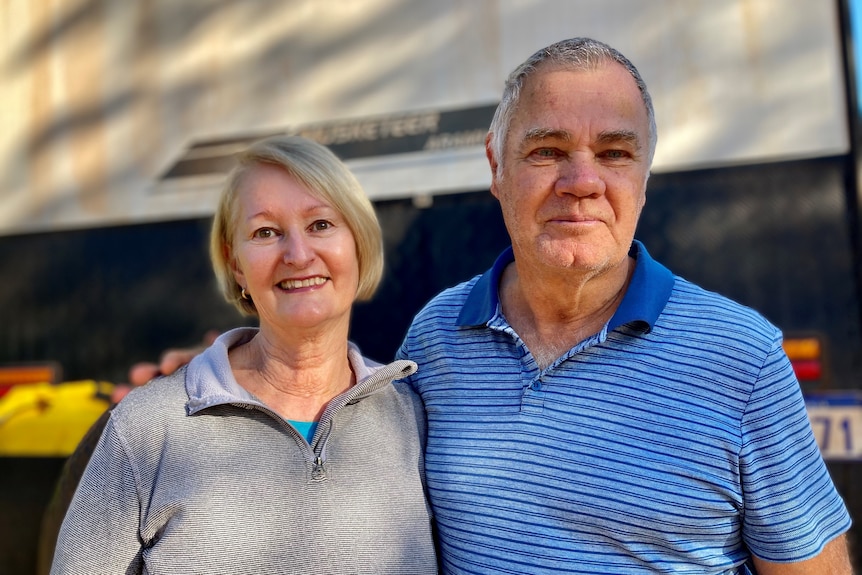 A couple stand together smiling.