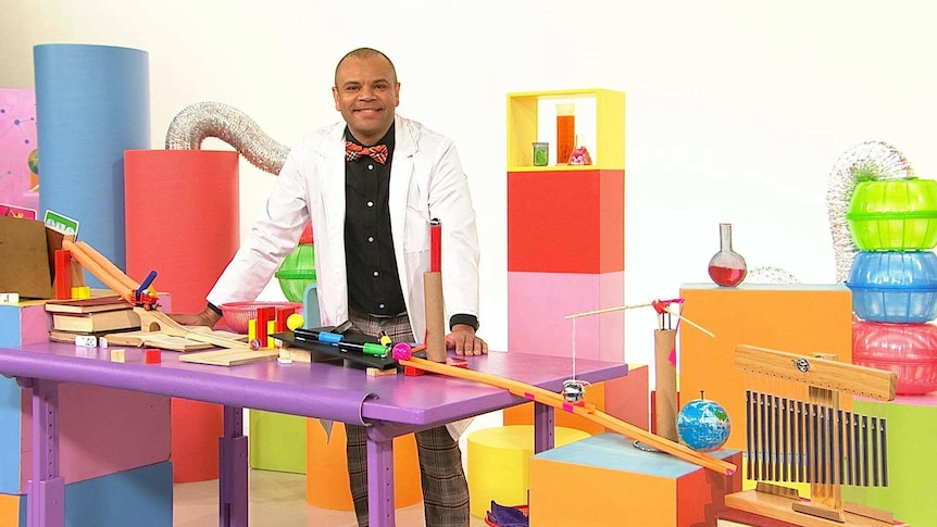 Luke on the Play School Science Time set wearing a lab coat with a chain reaction with different objects