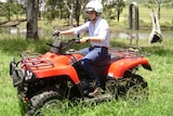 A young rider with a helmet on a quad bike with a roll bar.