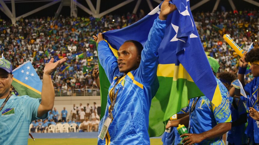 A Solomon Islands athlete holds the flag as he walks in the stadium.
