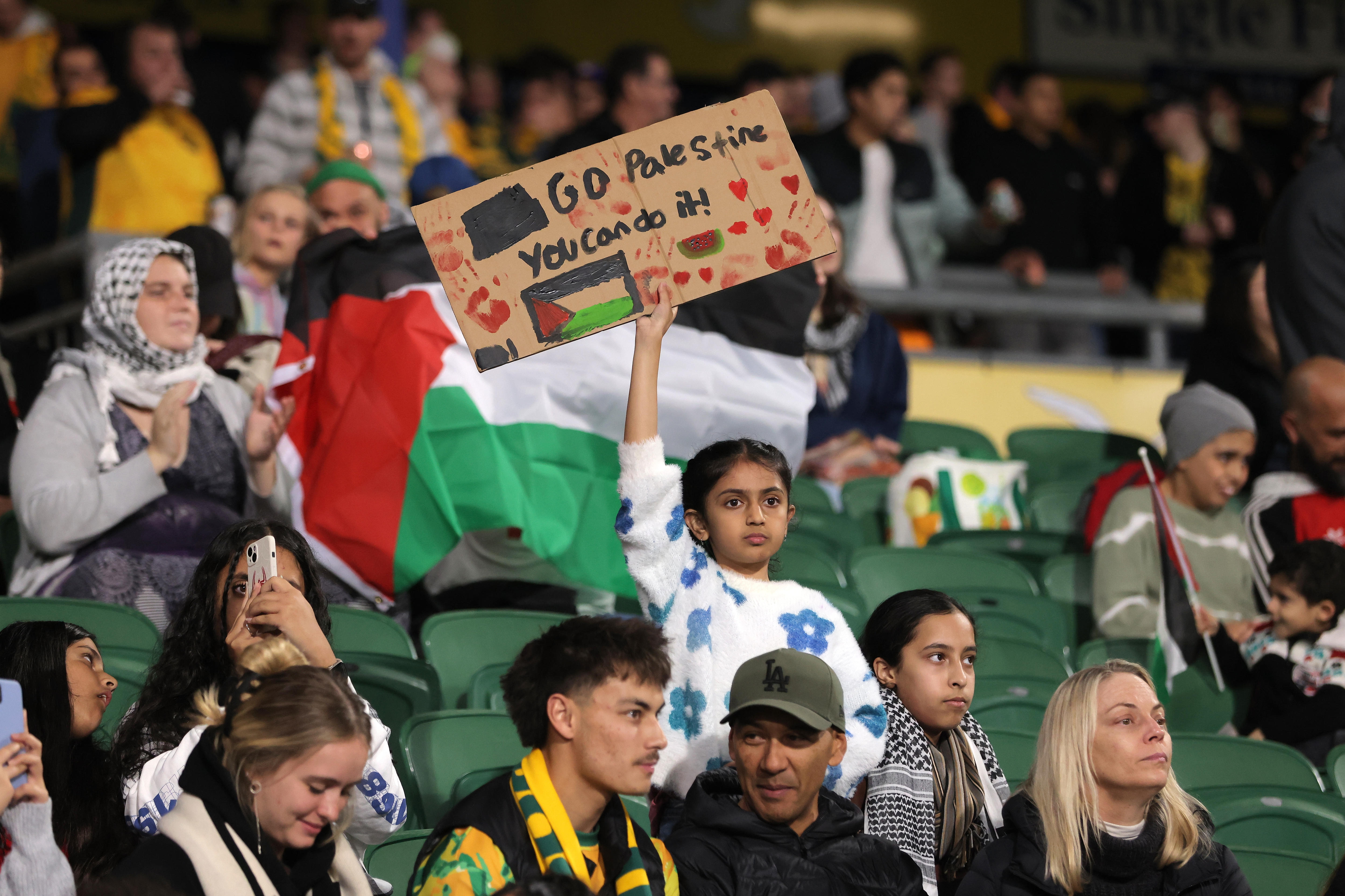 A crowd of football fans with placards supporting Palestine.