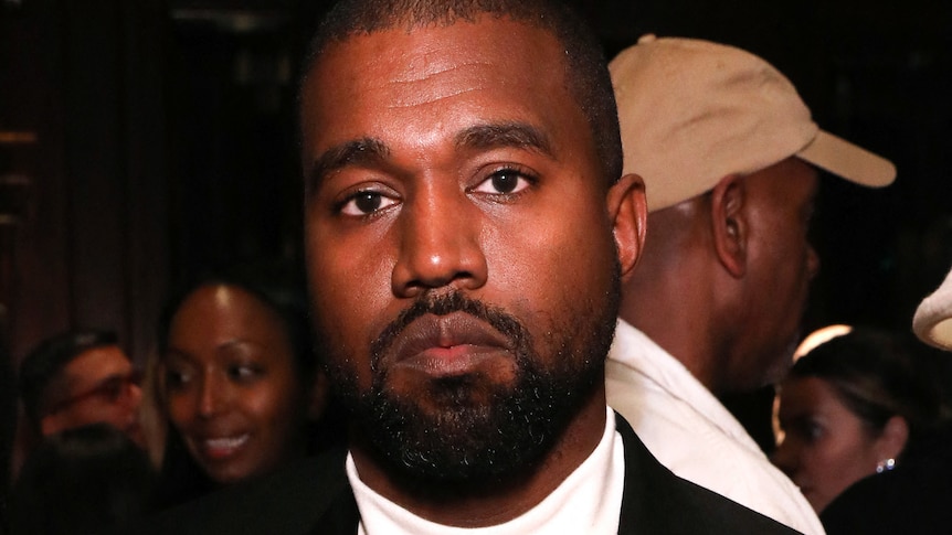 Kanye West, a black man, looking at the camera with a serious expression on his face.