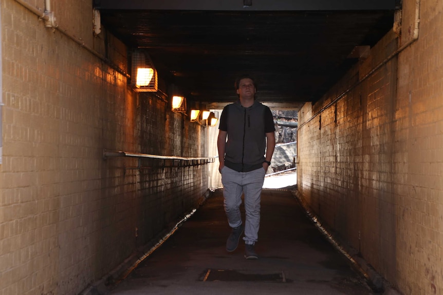 Allan Mclean walks through a low lit tunnel.