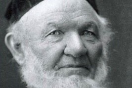 Black and white headshot of elderly man with grey hair and beard