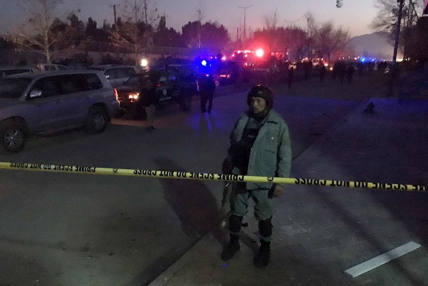 An Afghan policeman keeps watch near the site of a blast.