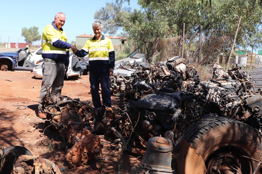 Two men in high vis inspect a car wreck