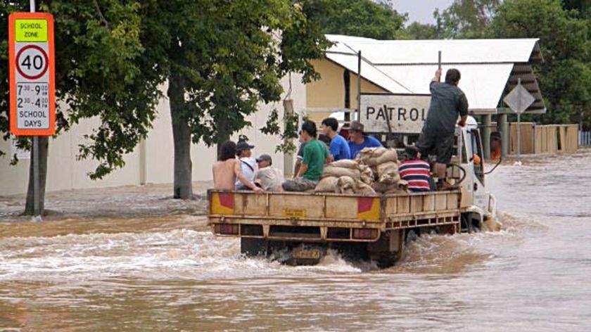 Charleville residents ride on a truck carrying sandbags