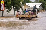 Charleville residents ride on a truck carrying sandbags
