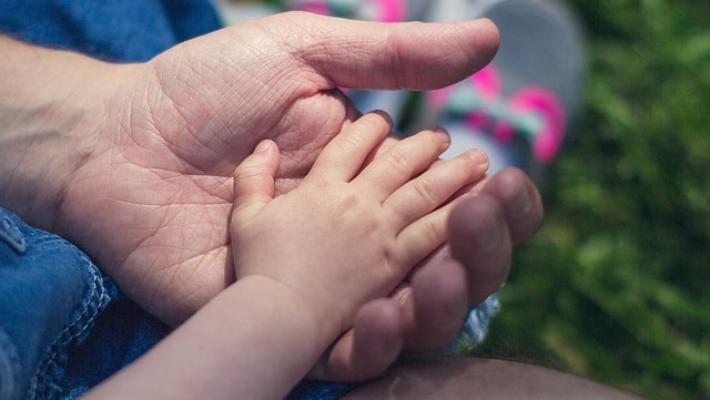 Adult male hand holds hand of a child.