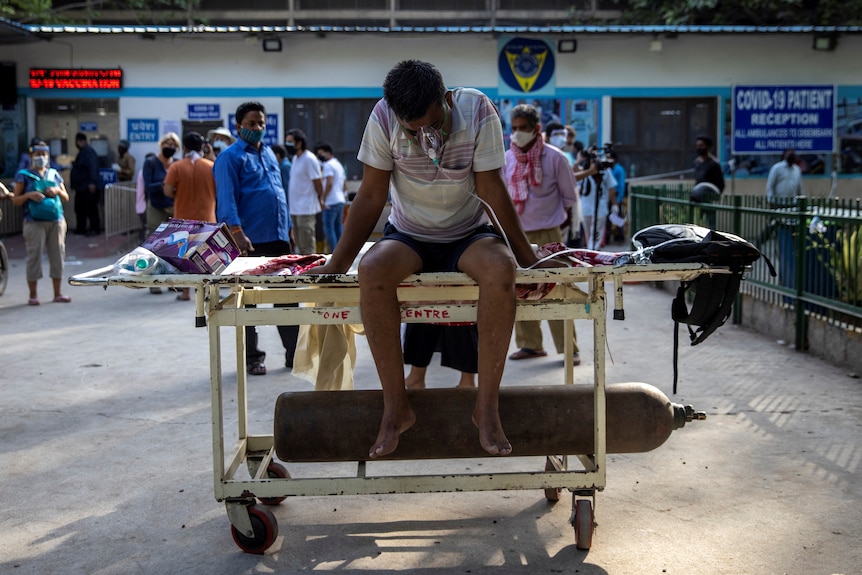 A COVID-19 patient waits outside a full New Delhi hospital