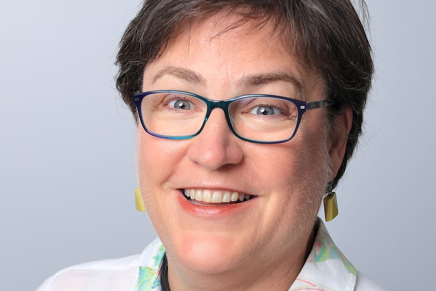 A professional head-shot of a woman who wears glasses 