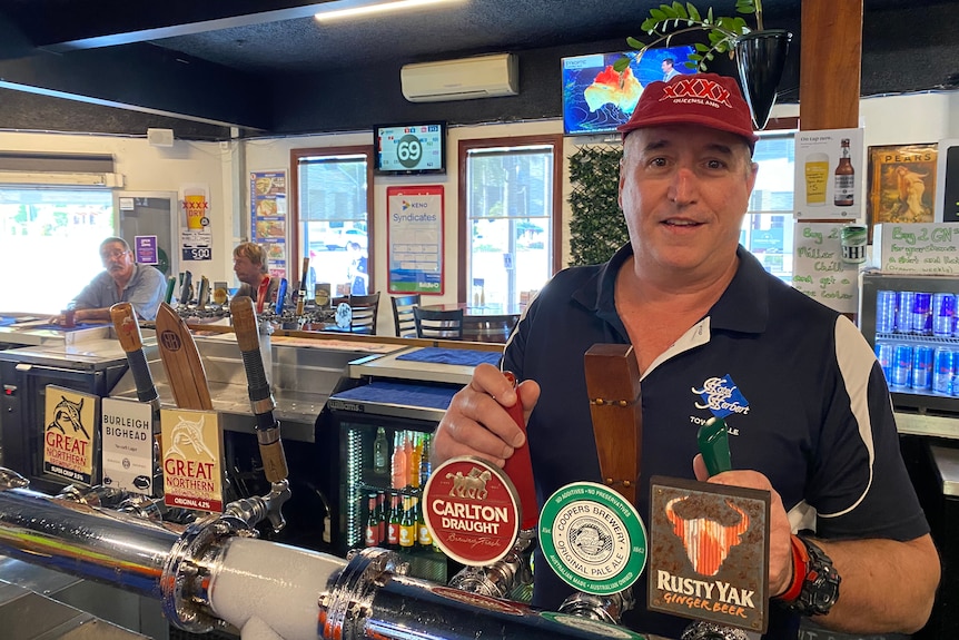 man wearing red hand with blue and white shirt stands behind a bar