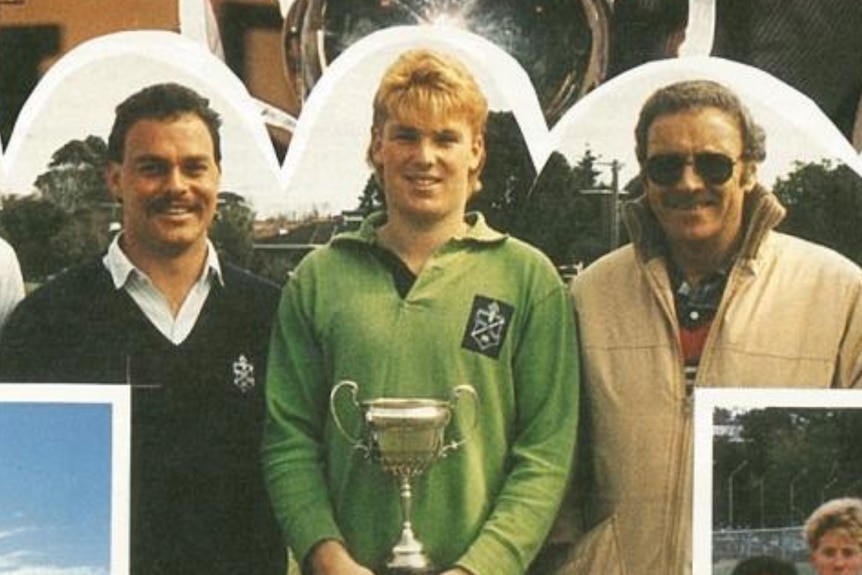 A young man with a trophy and his teachers