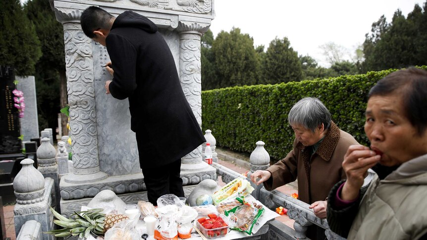People tend to a grave at Babaoshan Cemetery ahead of Qingming Festival, bringing food with them.