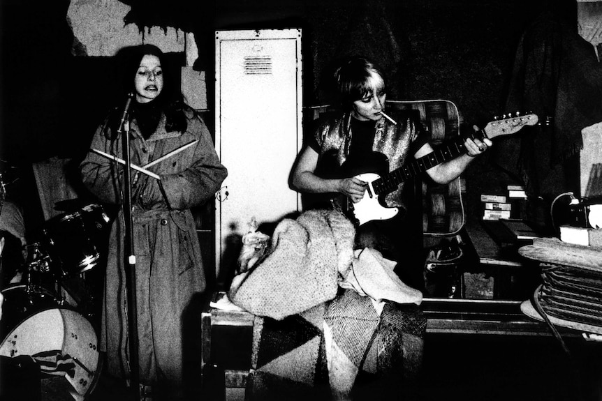 Black-and-white photograph of members of punk band The Slits rehearsing in a messy-looking room.